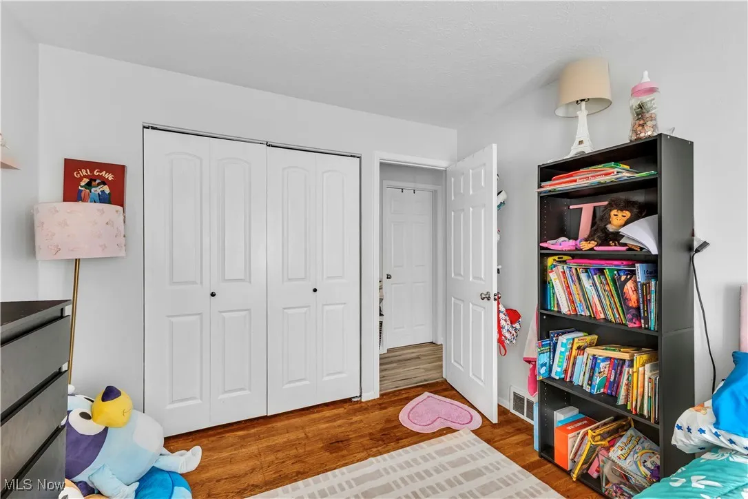 Bedroom with wood finished floors and a closet