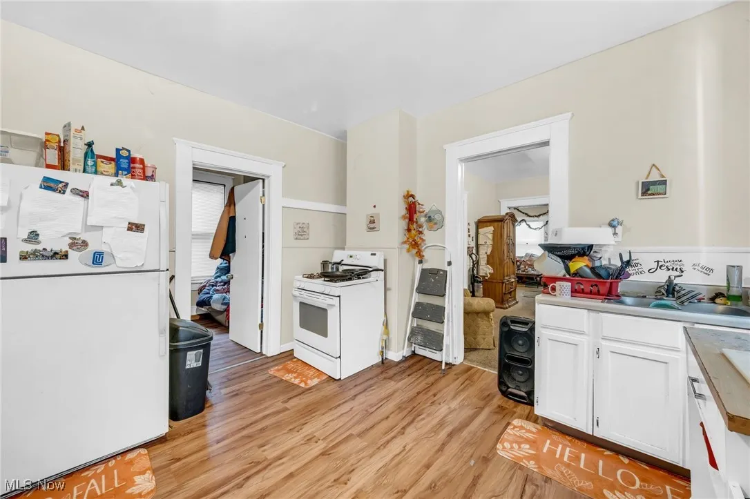 Kitchen featuring white appliances, white cabinets, light wood-style floors, and light countertops