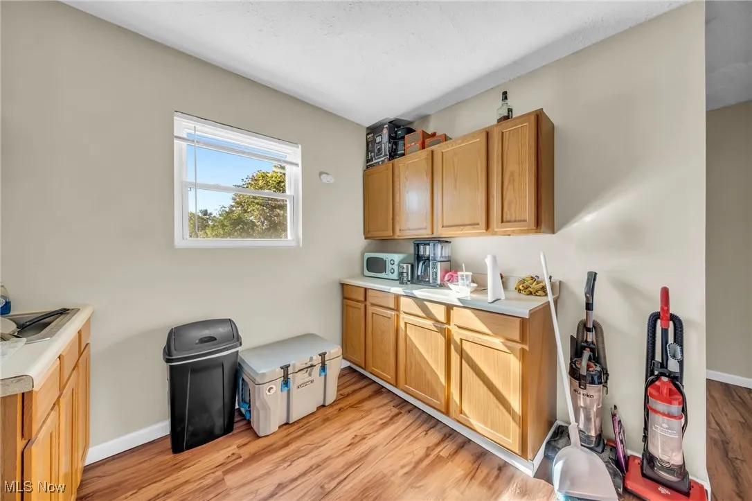 Kitchen featuring light countertops, light wood-type flooring, white microwave, and brown cabinets