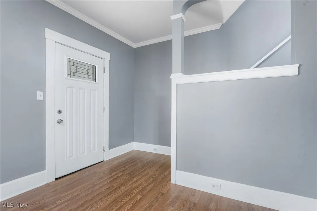 Foyer entrance with wood finished floors and ornamental molding