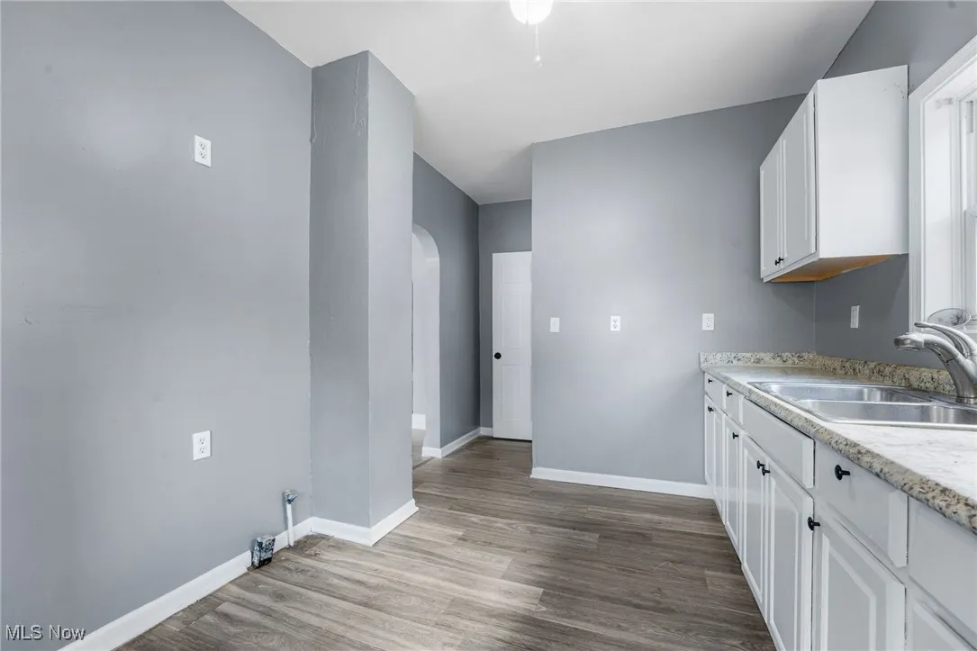 Kitchen with white cabinets, arched walkways, and dark wood-style floors