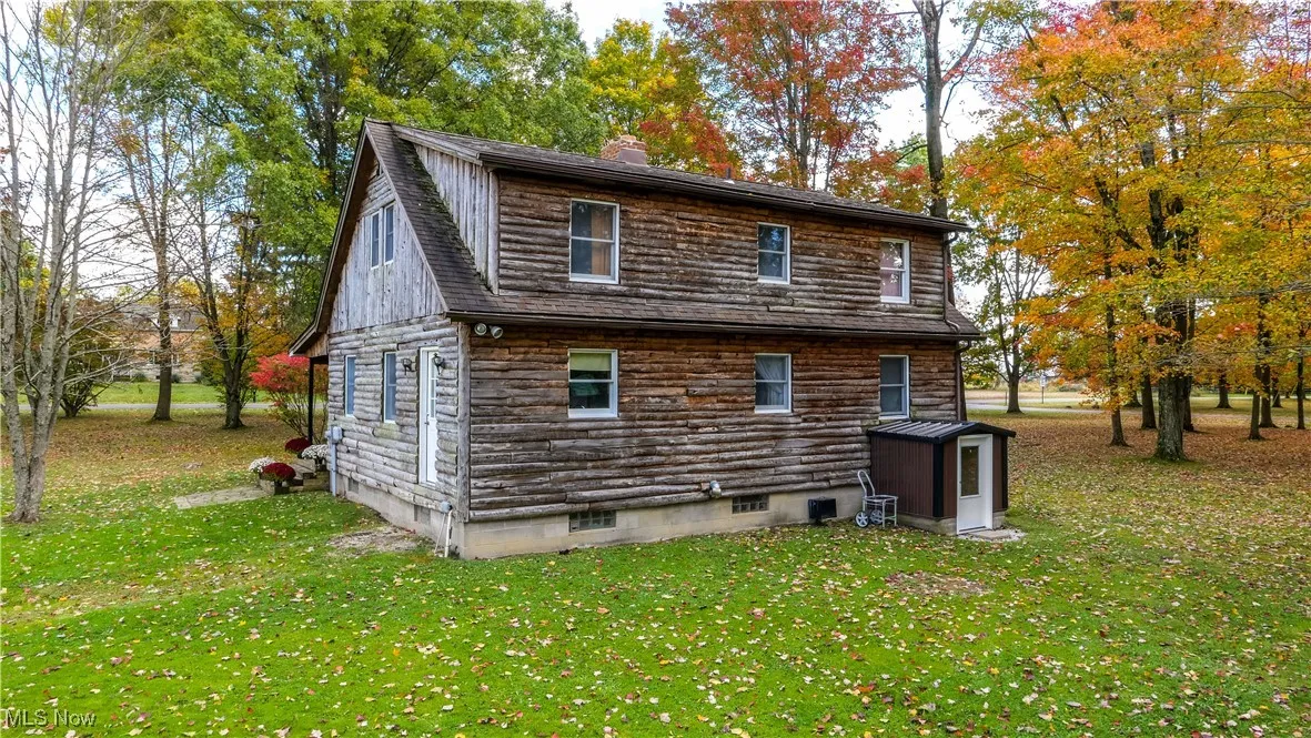 Rear view of property featuring a yard, a chimney, and stone siding
