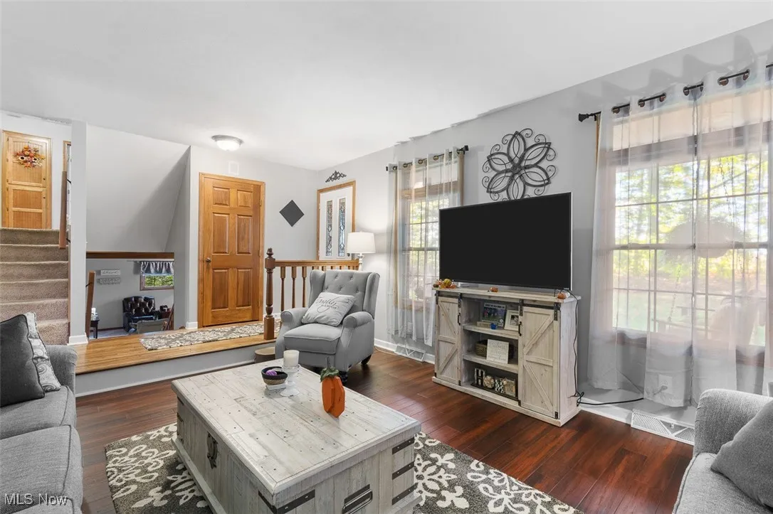 Living room with stairs and dark wood-style flooring