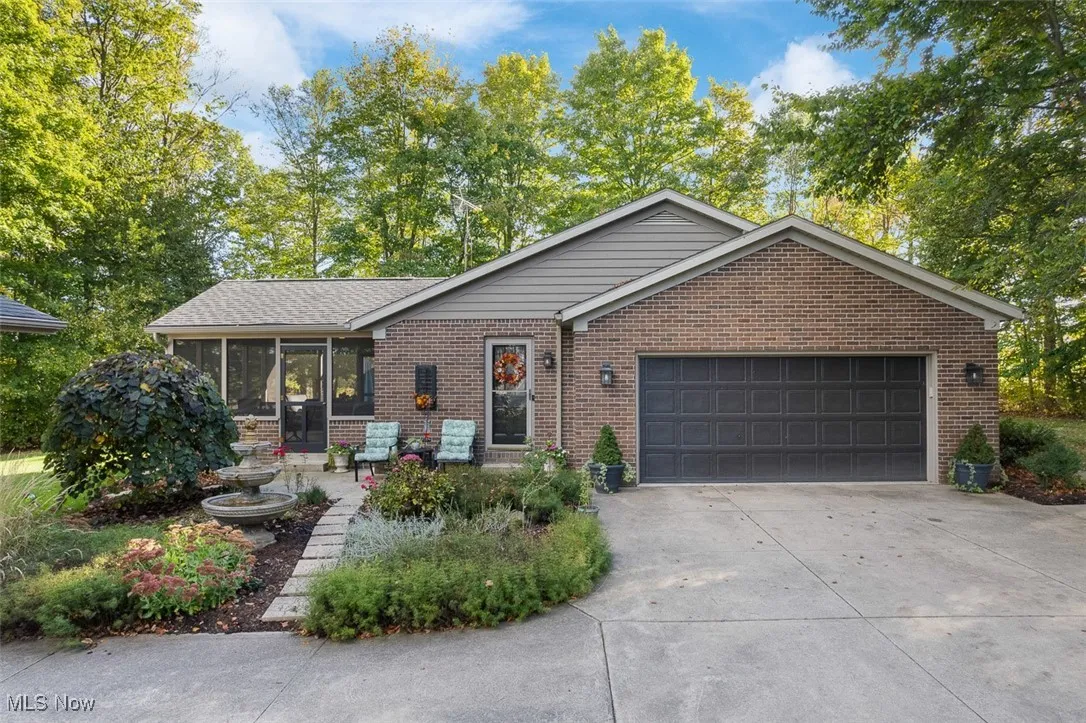 Ranch-style house featuring driveway, an attached garage, brick siding, and a sunroom
