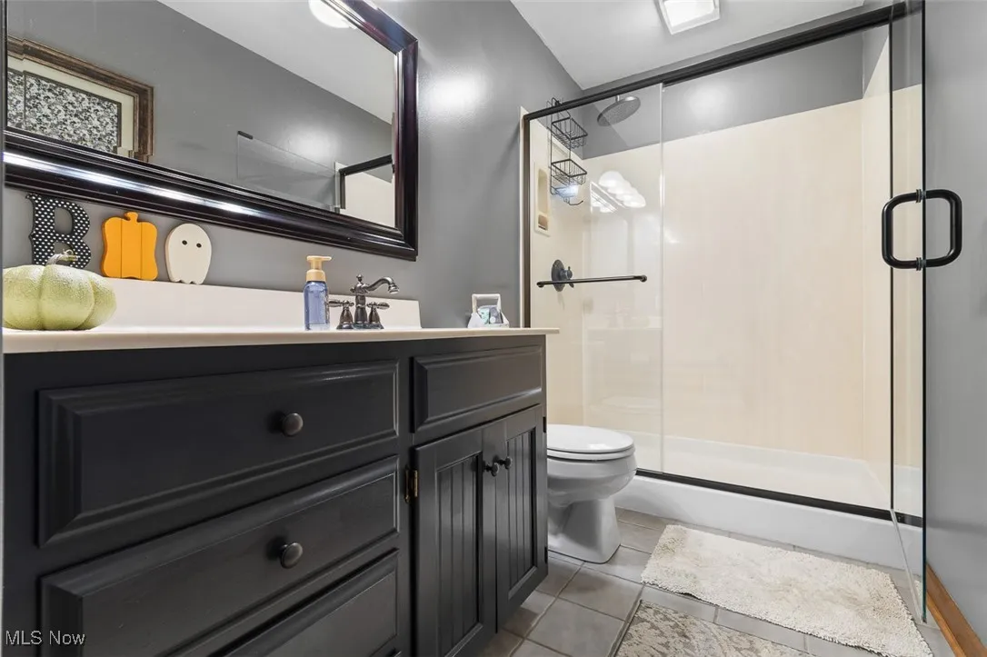 Bathroom featuring vanity, light tile patterned floors, and a stall shower