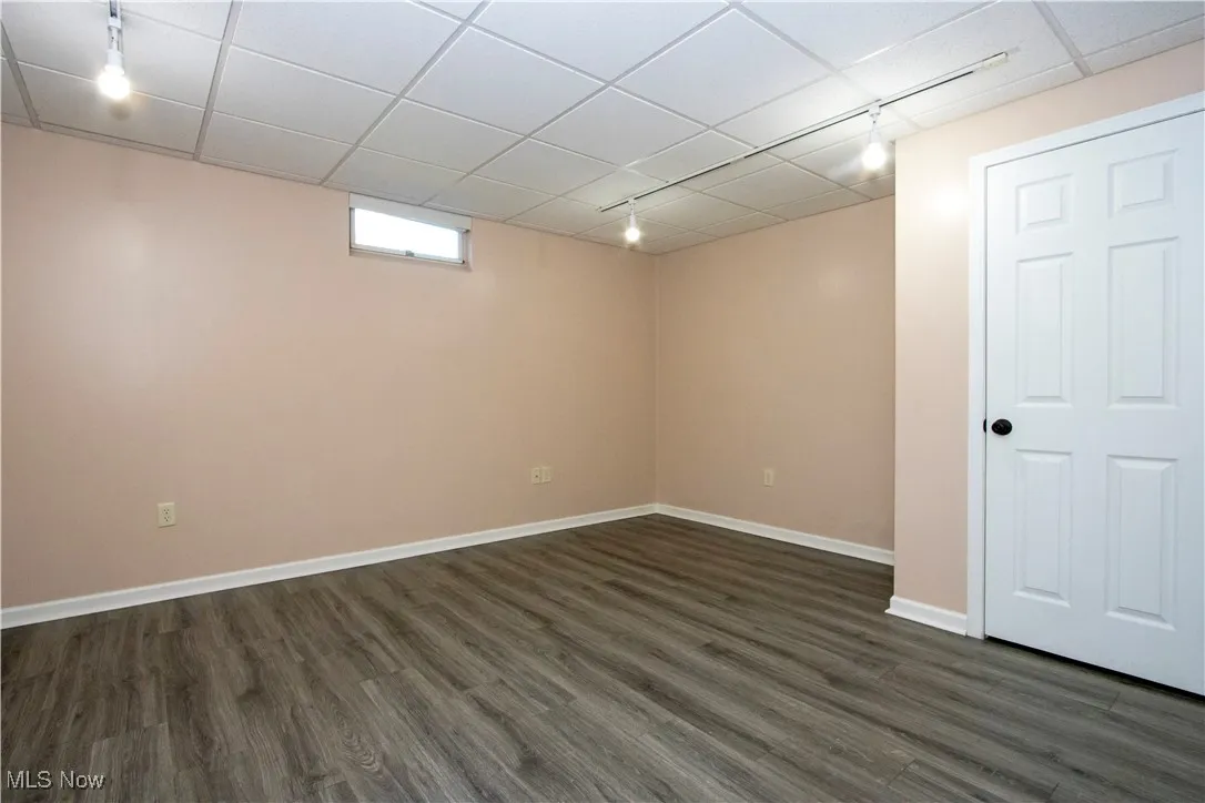 Below grade area with rail lighting, dark wood-style floors, and a drop ceiling