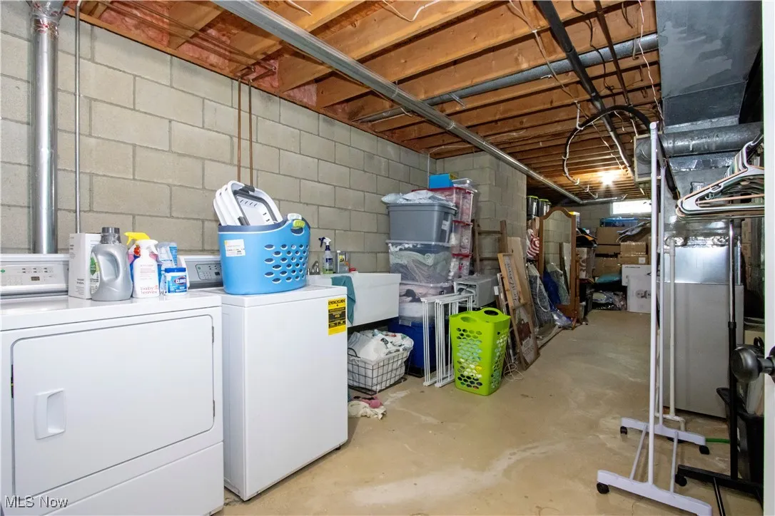 Unfinished below grade area featuring washing machine and dryer and heating unit