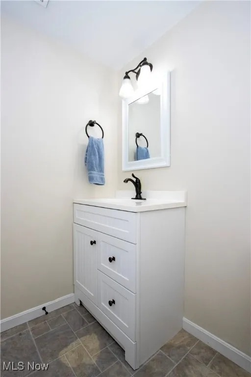 Half bath featuring vanity and baseboards