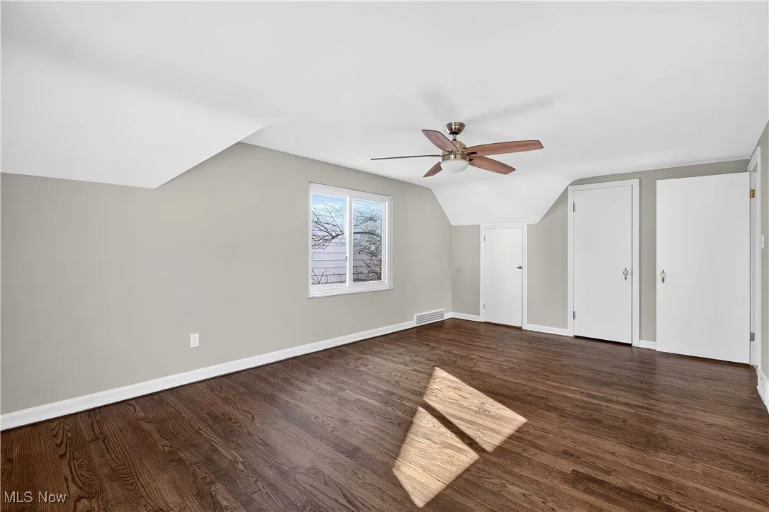 Bonus room featuring dark wood-style floors, vaulted ceiling, and ceiling fan