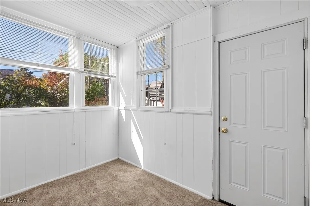 Unfurnished sunroom with wood walls and carpet flooring