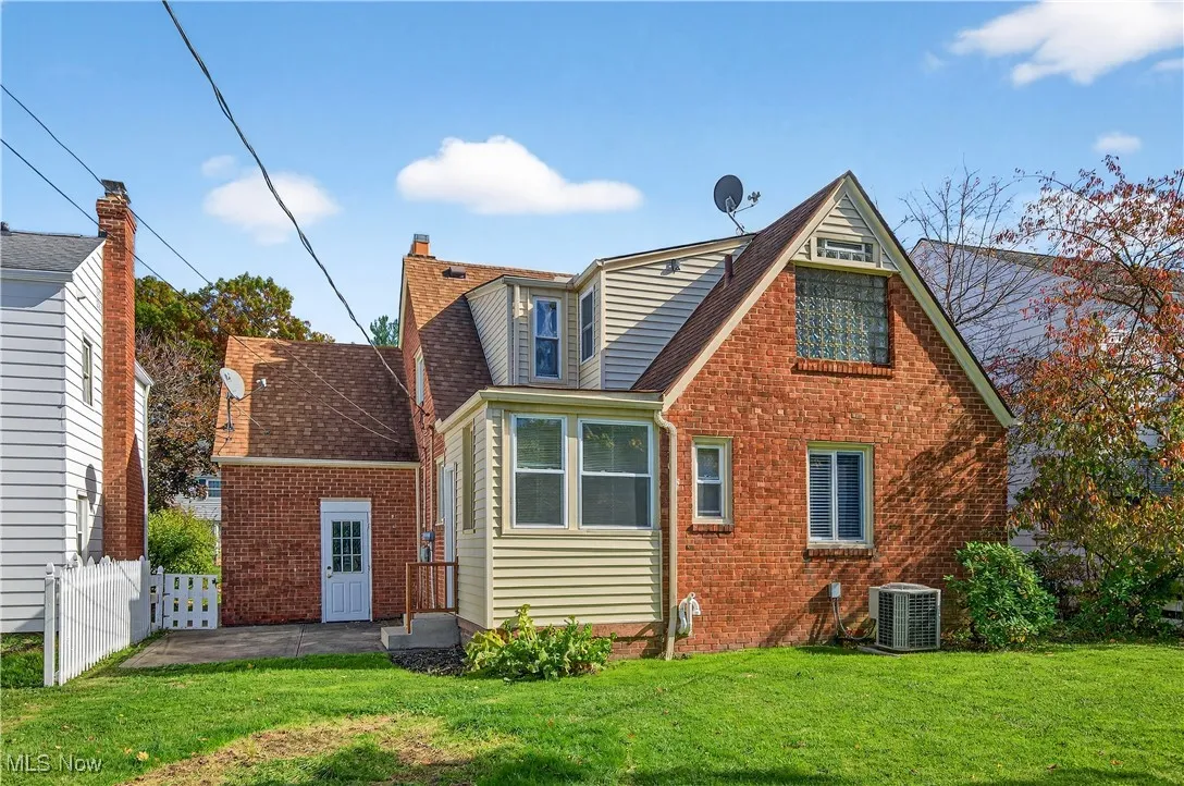 Rear view of property with brick siding, a shingled roof, and a patio area
