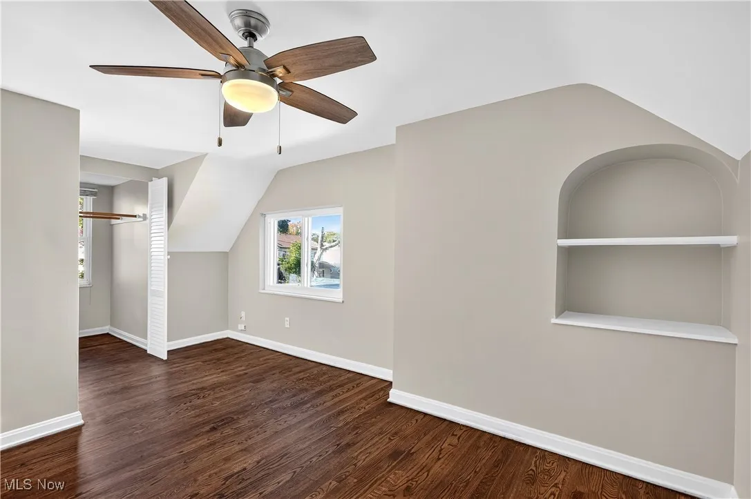 Additional living space featuring dark wood-style flooring, lofted ceiling, and ceiling fan