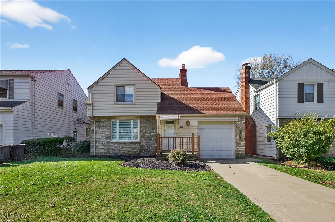 View of front of house featuring stone siding, a front lawn, a garage, and driveway