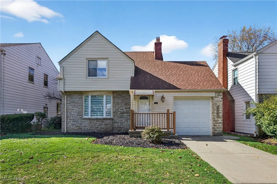 View of front of house featuring stone siding, an attached garage, a front yard, driveway, and a chimney