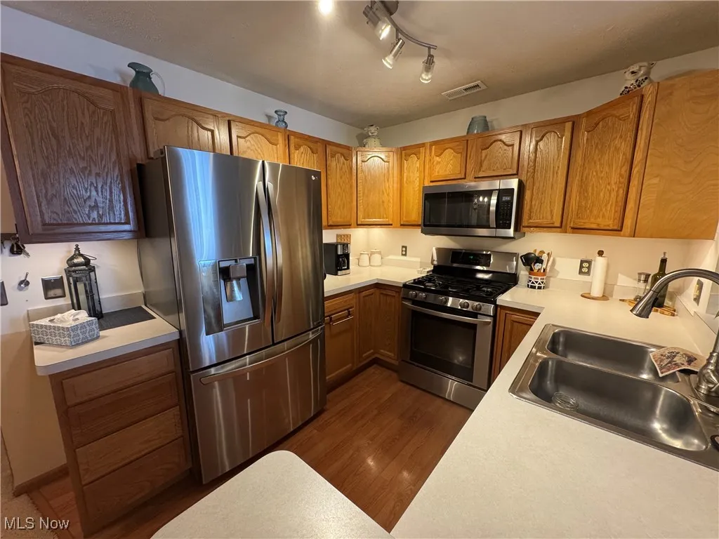 Kitchen with appliances with stainless steel finishes, light countertops and rail lighting