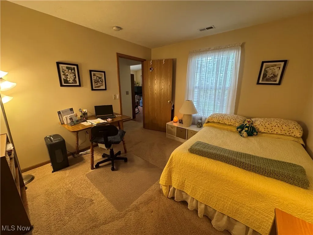 Bedroom with an office area and light colored carpet