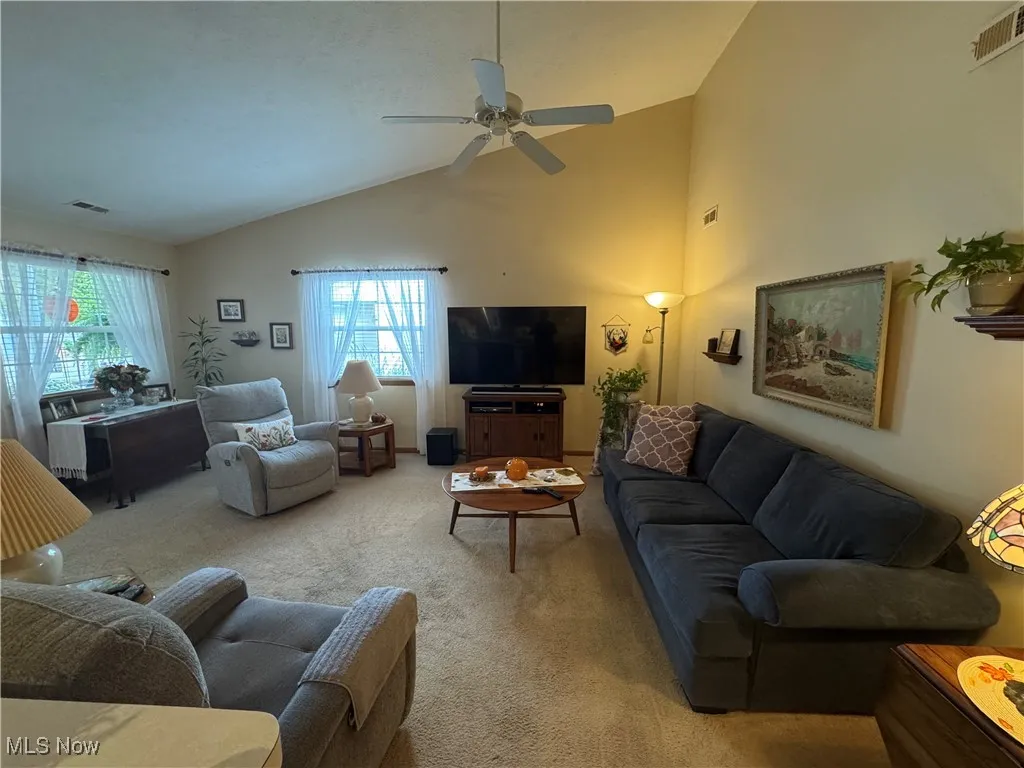 Living area with high vaulted ceiling, carpet floors, and ceiling fan