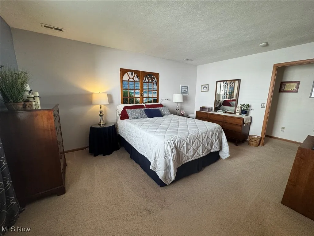 Bedroom featuring light colored carpet and a textured ceiling