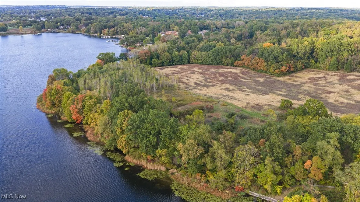 Aerial view of property's location with a nearby body of water and a heavily wooded area