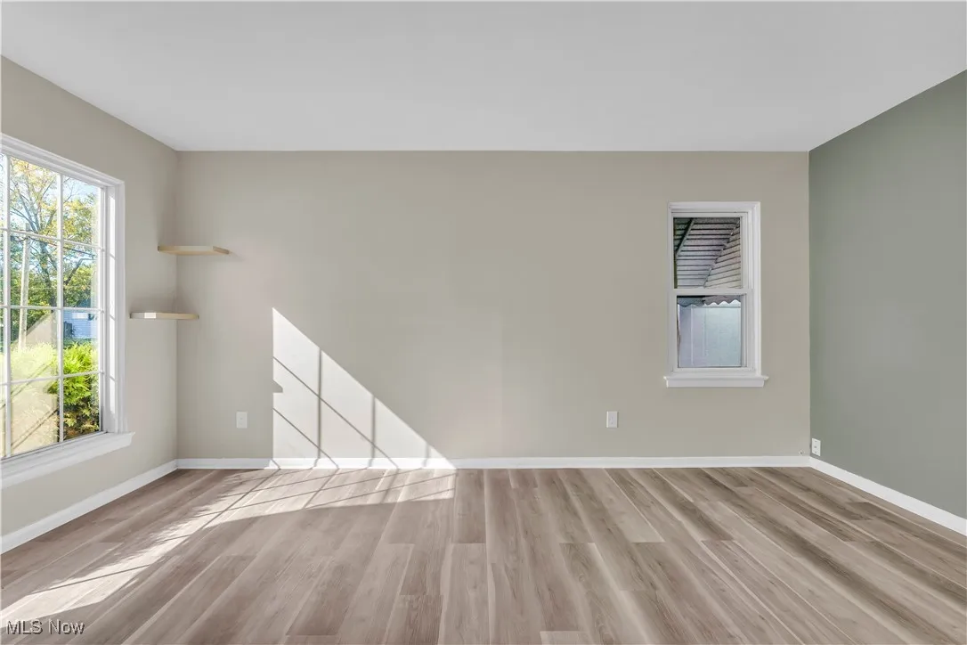 Empty room with light wood-type flooring and plenty of natural light