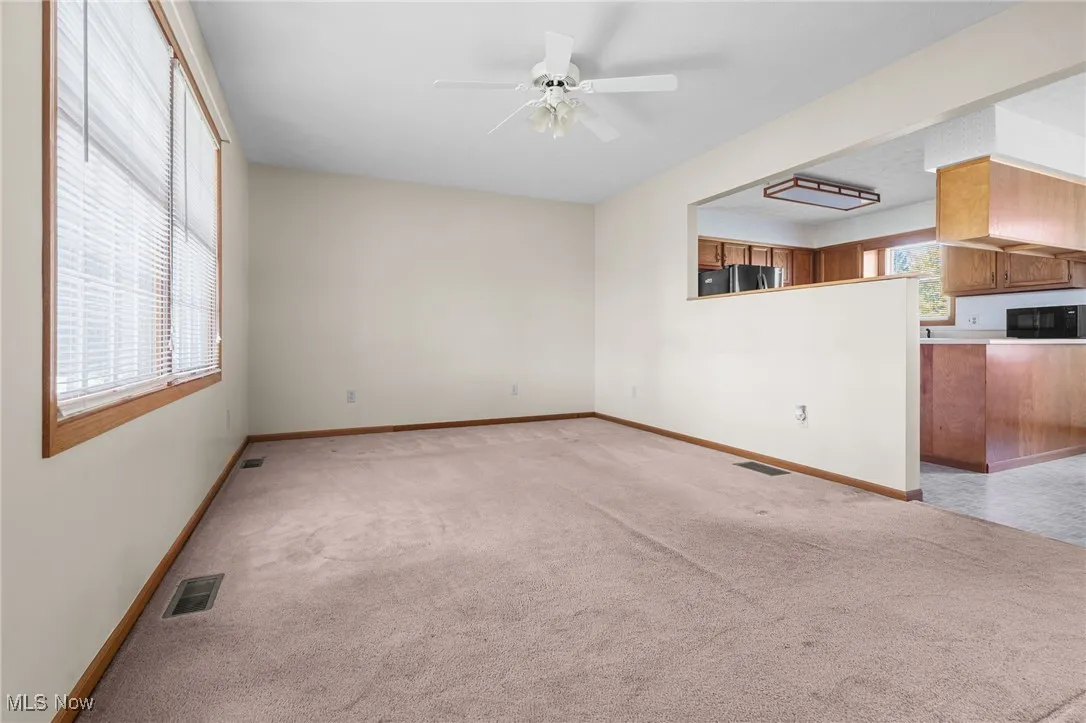 Unfurnished living room featuring light carpet and ceiling fan