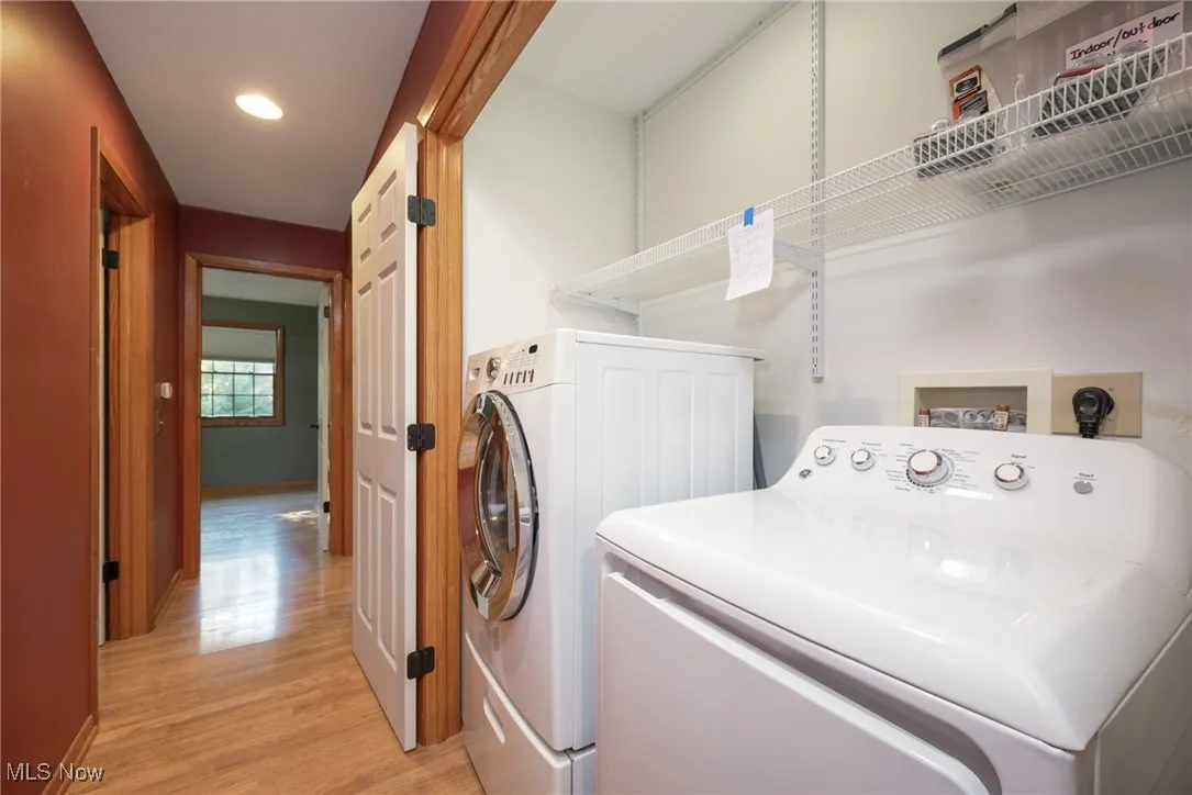 Washroom featuring light wood finished floors, washing machine and dryer, and recessed lighting