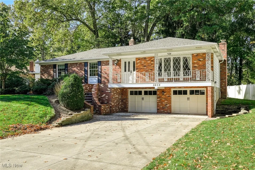 View of front of property with a chimney, a front lawn, a balcony, and brick siding
