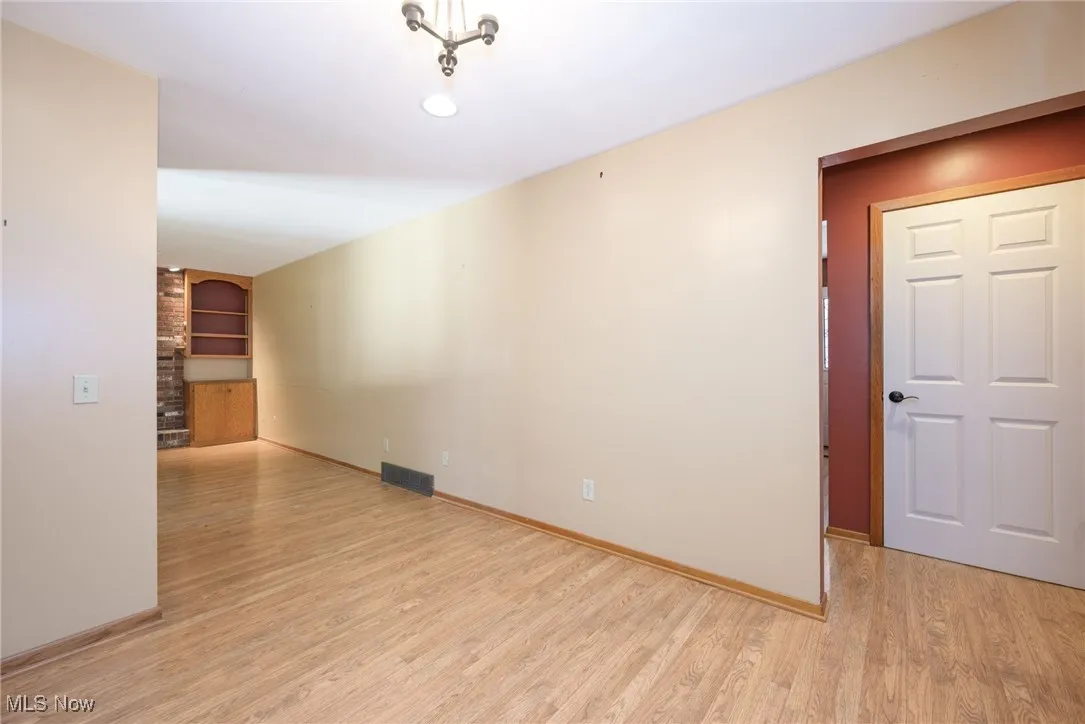Unfurnished room featuring built in shelves and light wood-style flooring