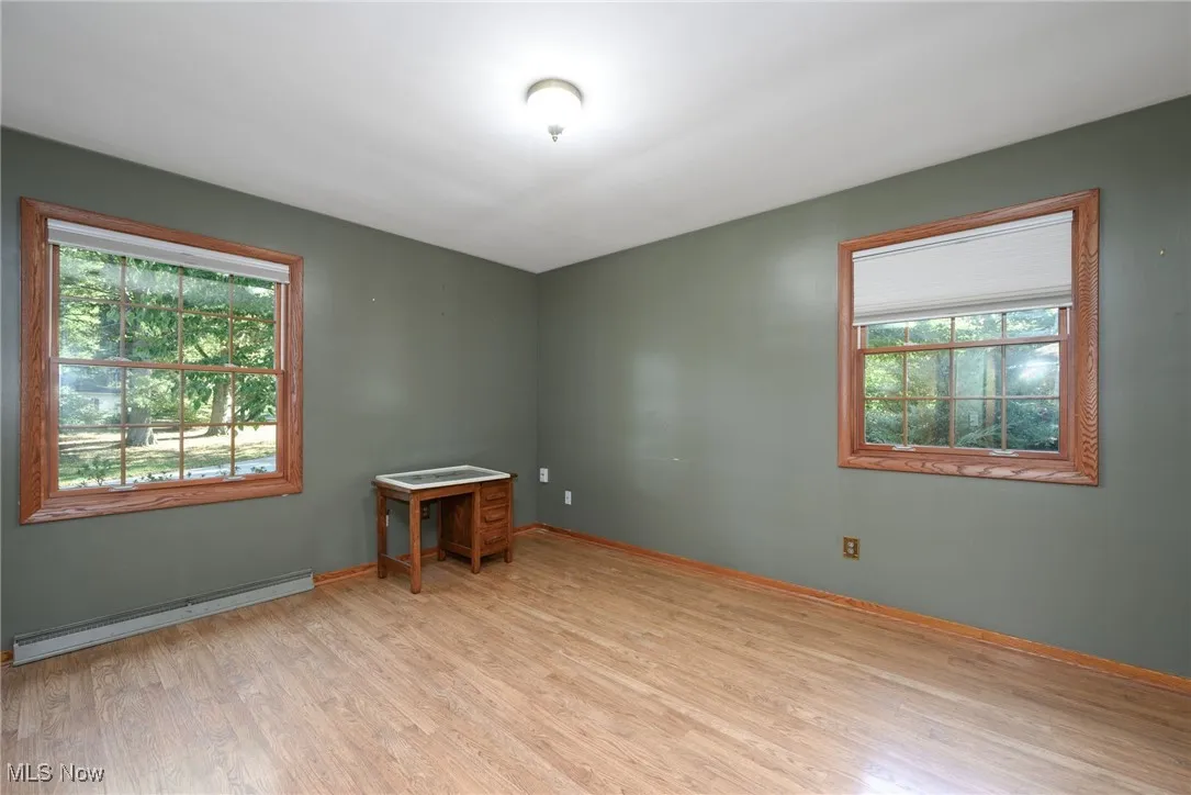 Unfurnished room with baseboard heating and light wood-style floors