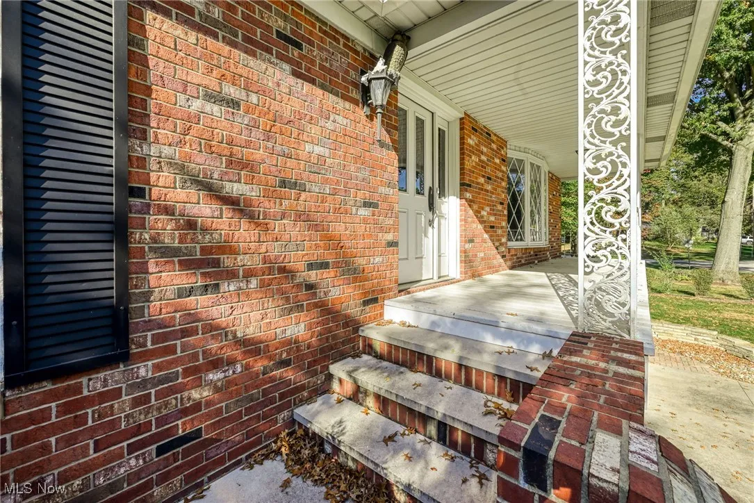 View of exterior entry featuring brick siding and a porch