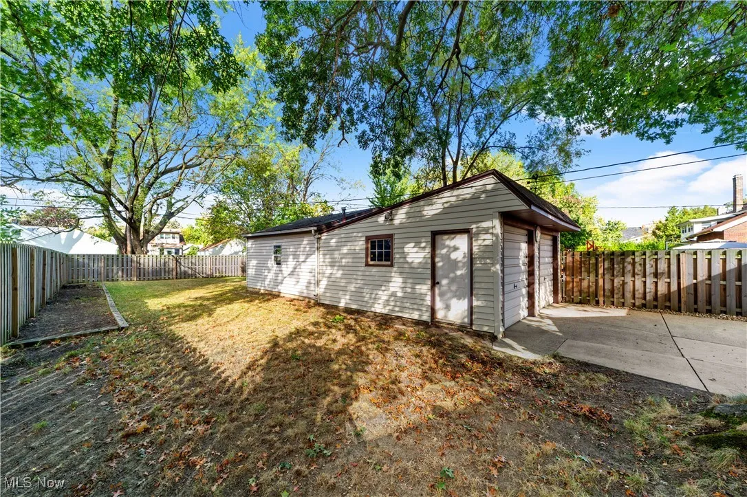 Back of property featuring a fenced backyard, an outbuilding, and a garage