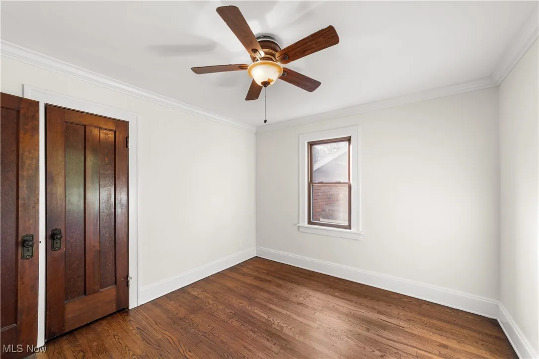 Unfurnished bedroom with crown molding, dark wood-type flooring, and ceiling fan