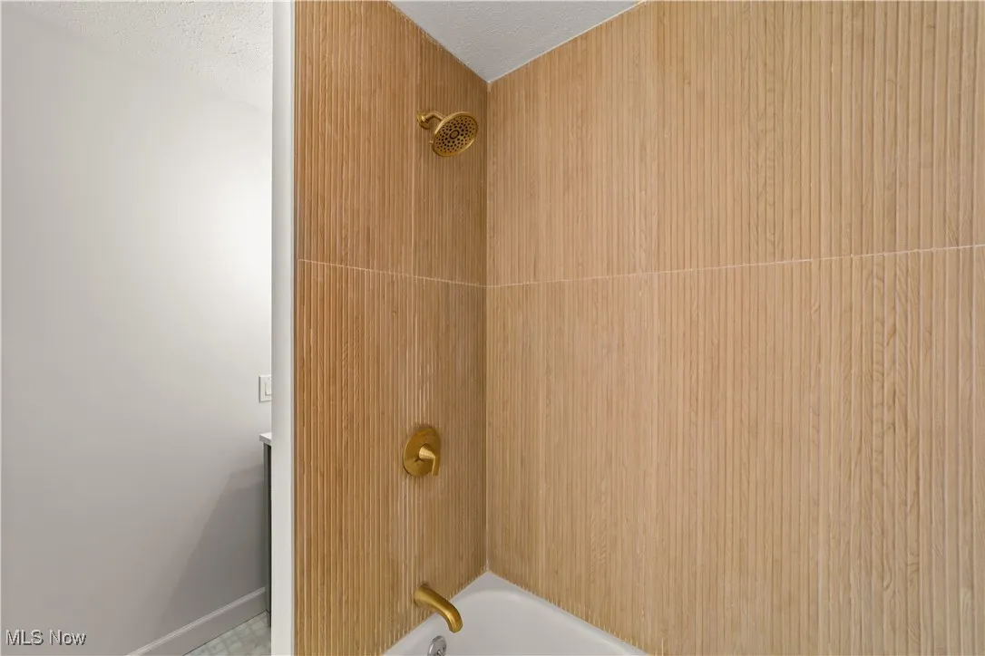 Bathroom view of shower / bath combination and a textured ceiling