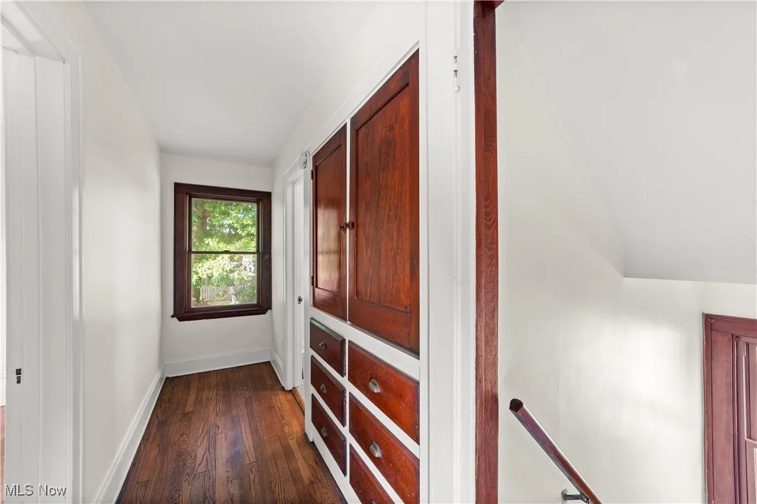 Hallway featuring dark wood-style floors and an upstairs landing