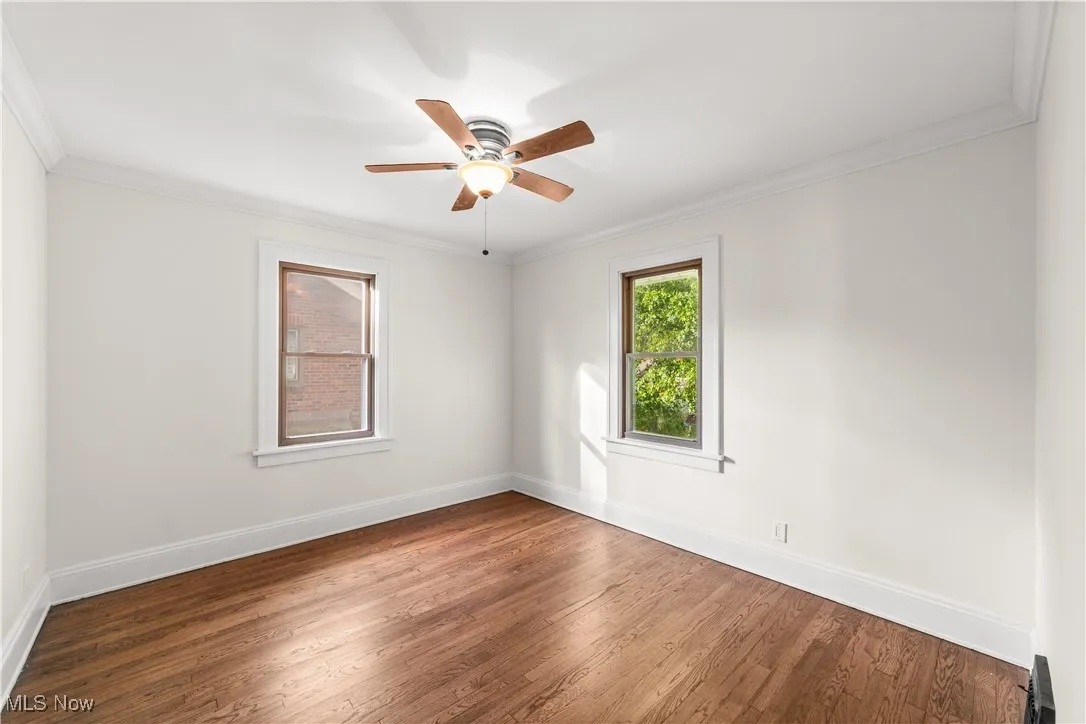 Unfurnished room with ornamental molding, wood finished floors, and a ceiling fan