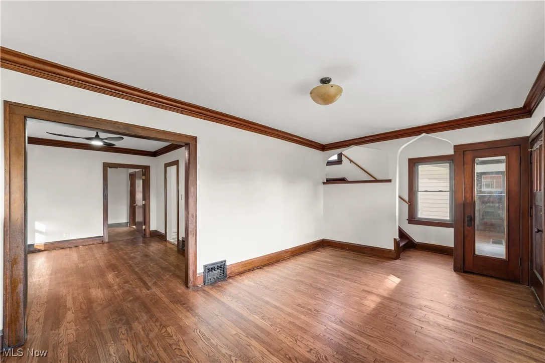 Unfurnished room featuring ornamental molding, stairway, dark wood-style floors, and a ceiling fan