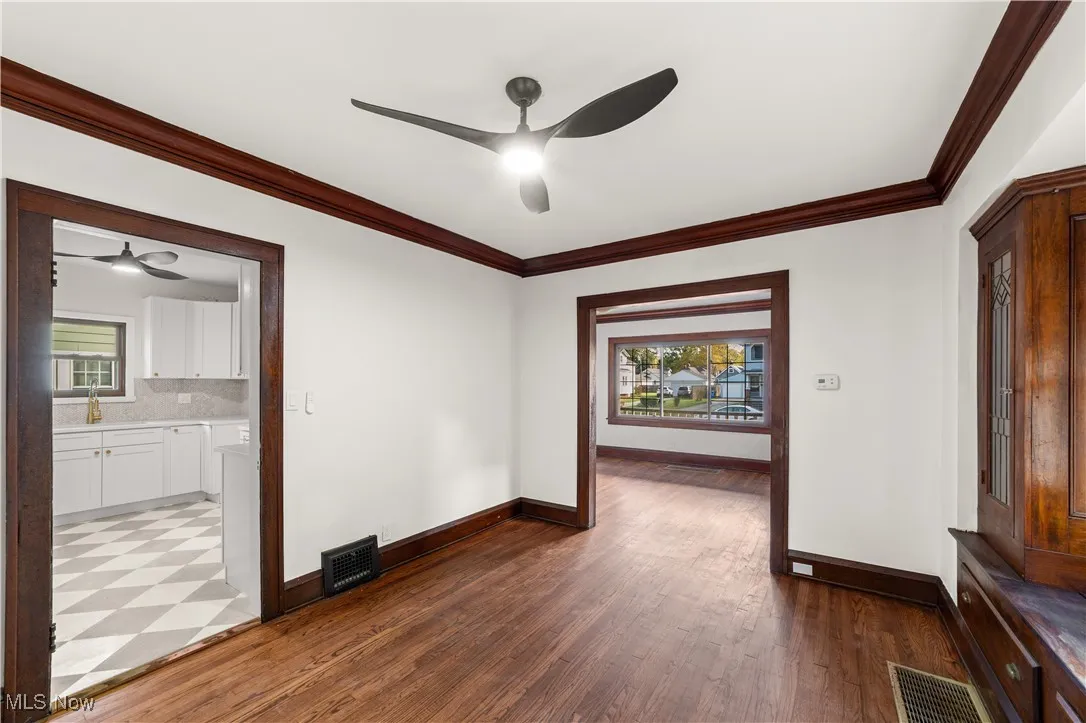 Spare room with ornamental molding, a ceiling fan, and dark wood-type flooring
