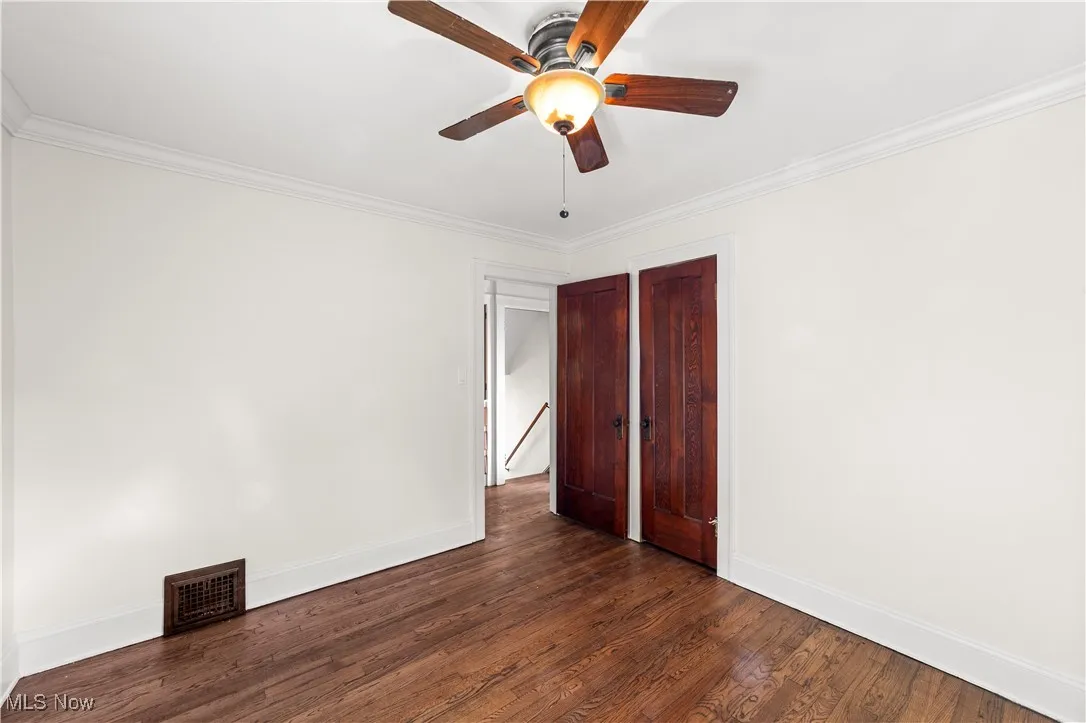 Spare room with ornamental molding, dark wood-style floors, and ceiling fan