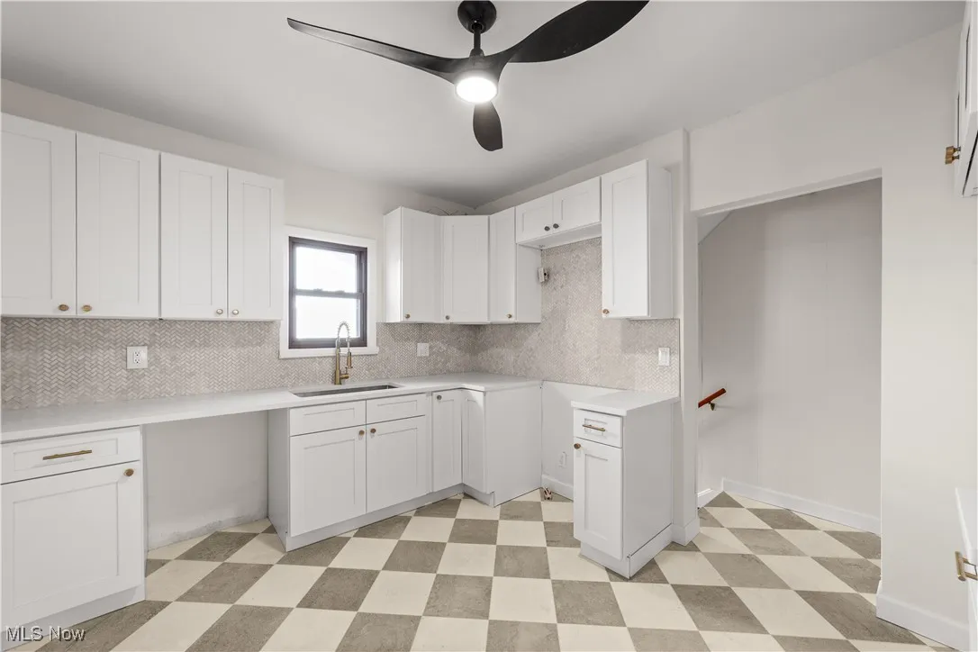 Kitchen featuring light floors, white cabinets, backsplash, and a ceiling fan