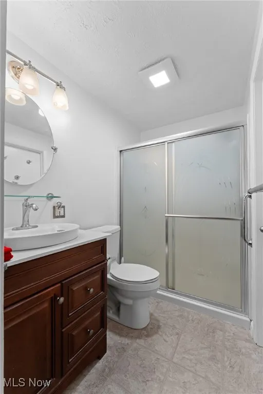 Bathroom featuring vanity, a marble finish shower, and a textured ceiling