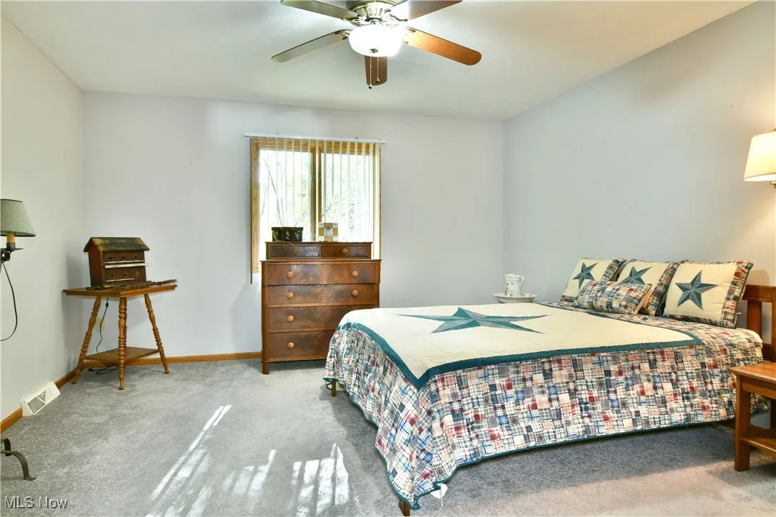 Carpeted bedroom with ceiling fan and baseboards