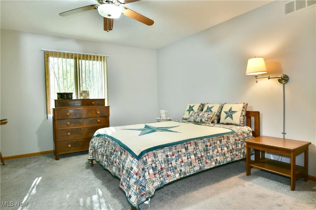 Bedroom with light colored carpet and a ceiling fan