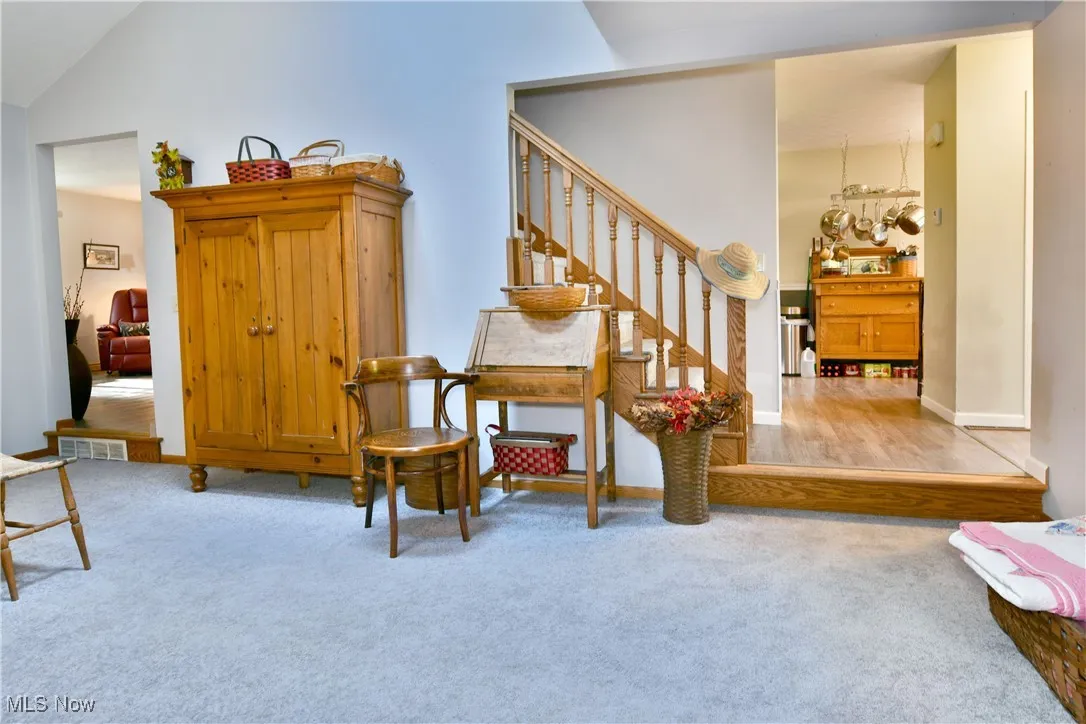 Living area with light colored carpet, stairs, lofted ceiling, and light wood finished floors