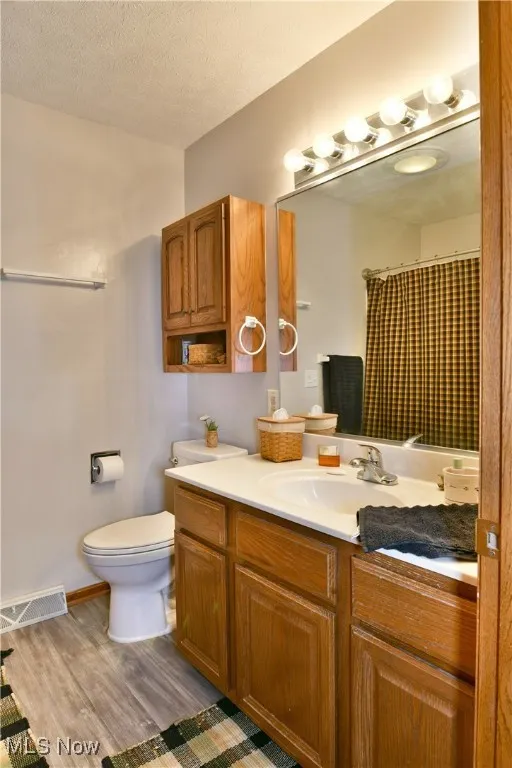 Bathroom featuring vanity, a shower with curtain, light wood-style floors, and a textured ceiling
