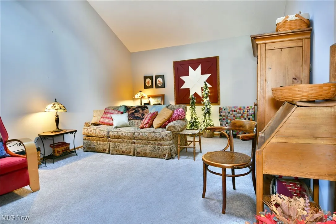 Living area with carpet floors and vaulted ceiling