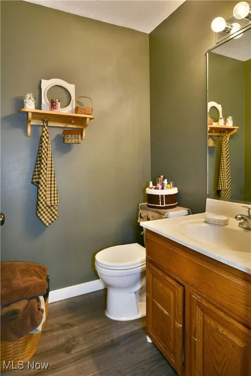 Half bathroom featuring vanity, dark wood-style floors, and a textured ceiling