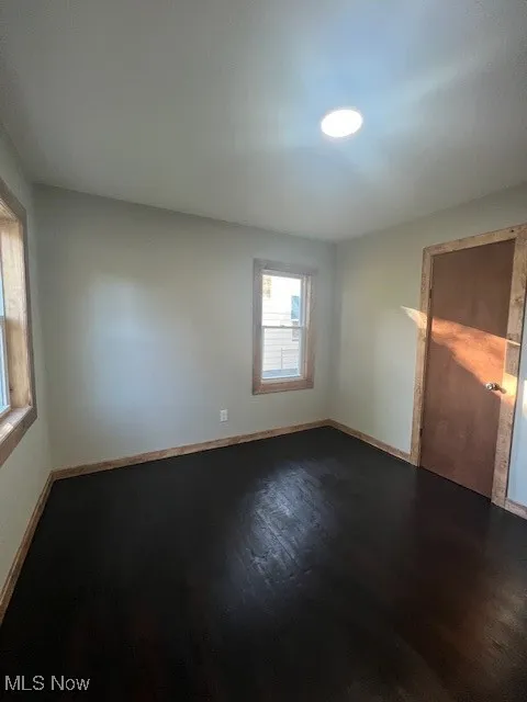 Unfurnished bedroom with wood finished floors and baseboards