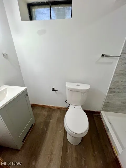 Bathroom with vanity, a shower stall, and dark wood-style flooring