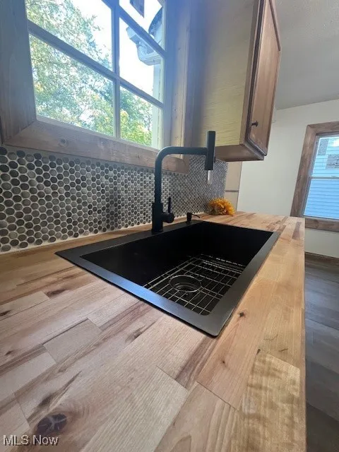 Kitchen view of wooden counters, dark wood-style floors, and tasteful backsplash