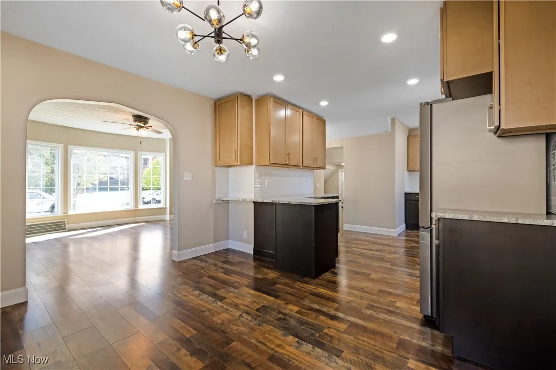 Kitchen featuring backsplash, freestanding refrigerator, ceiling fan, open floor plan, and arched walkways